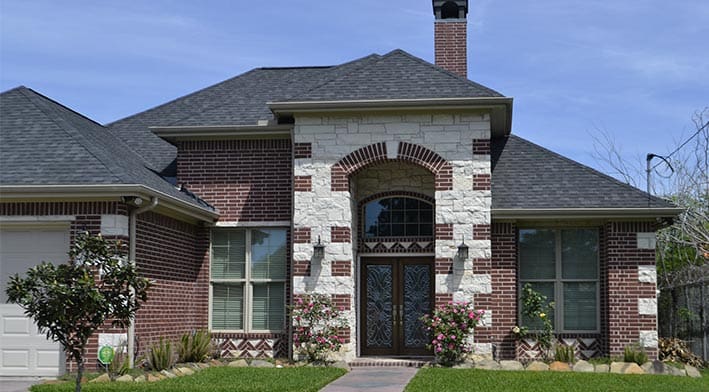 A brick house with a black roof and white trim.