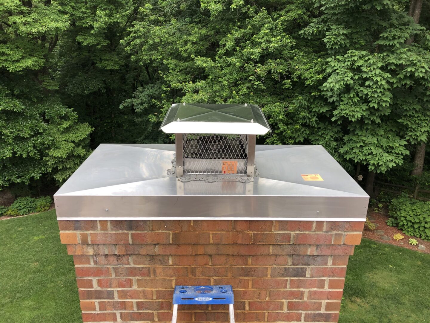 A stainless steel chimney cap on top of a brick building.